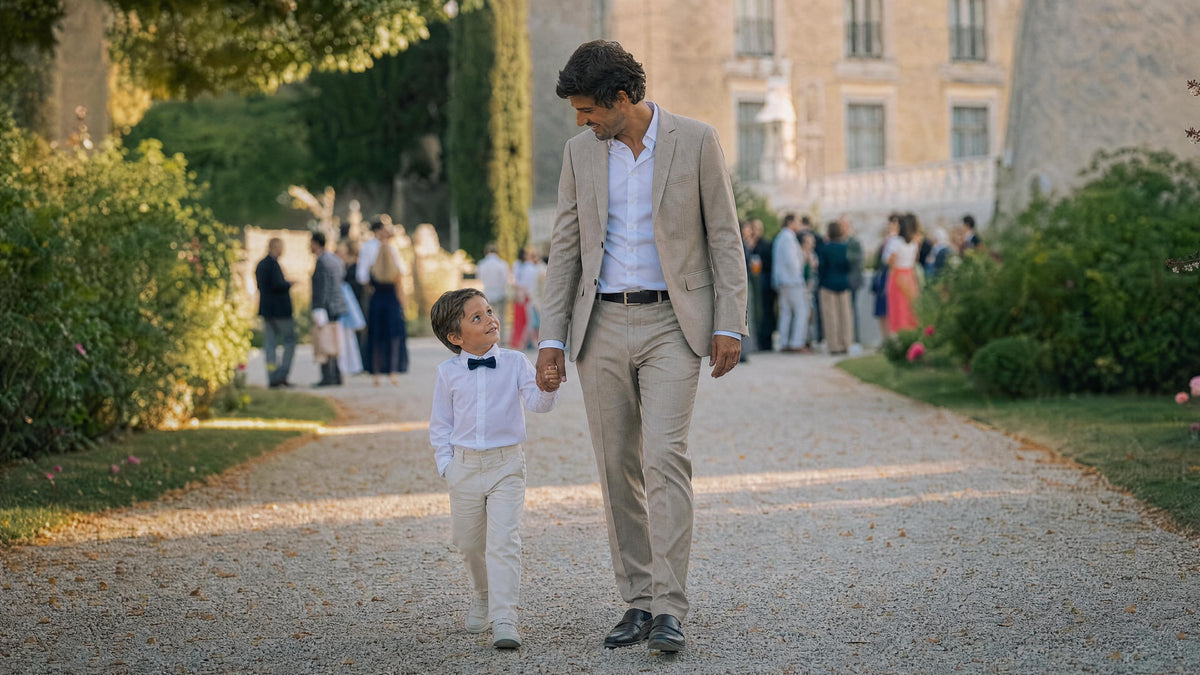 Enfant habillé pour un mariage marchant avec un adulte, tenue élégante et confortable. Billede